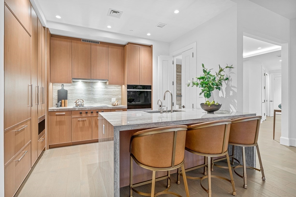40 Trinity Place, Unit PH35D Boston, MA 02116 - Photo 29 of 40 a kitchen with kitchen island granite countertop wooden cabinets and stainless steel appliances