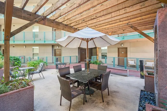 a view of a patio with a dining table and chairs under an umbrella