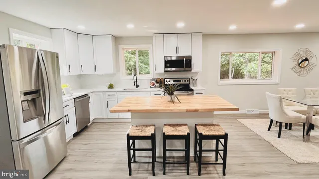 a kitchen with stainless steel appliances granite countertop a dining table chairs refrigerator and microwave