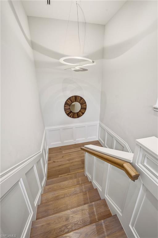 215 3rd Avenue North Naples, FL 34102 - Photo 22 of 47 Stairway featuring a decorative wall, a wainscoted wall, and wood finished floors