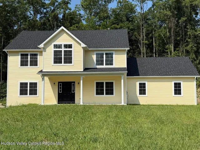 a view of a yard in front of a house with plants and large tree