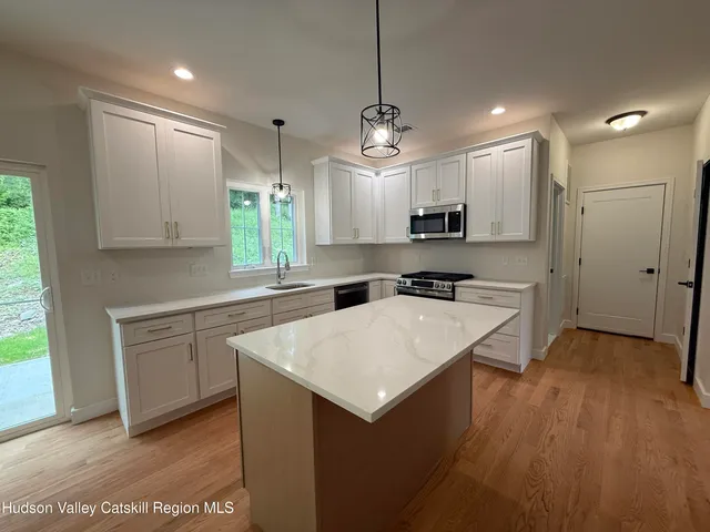 a kitchen with a refrigerator a sink dishwasher a stove and white cabinets with wooden floor