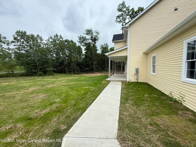 a view of a white house in front of a yard with many windows