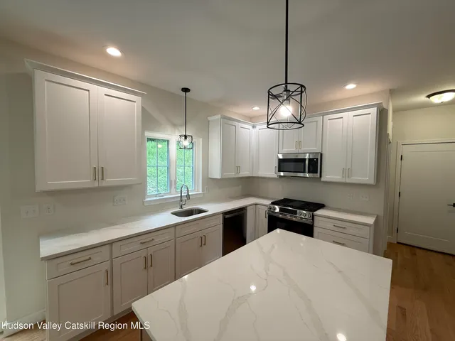 a kitchen with a white center island a sink stainless steel appliances and cabinets