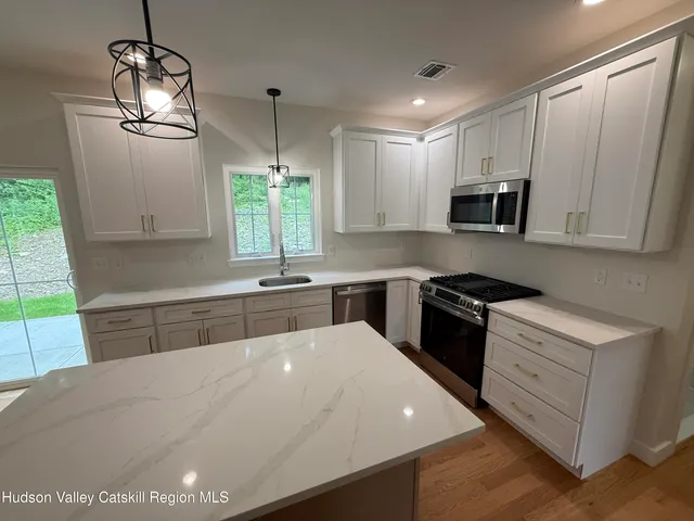 a kitchen with stainless steel appliances a sink dishwasher a stove a microwave oven with cabinets and wooden floor