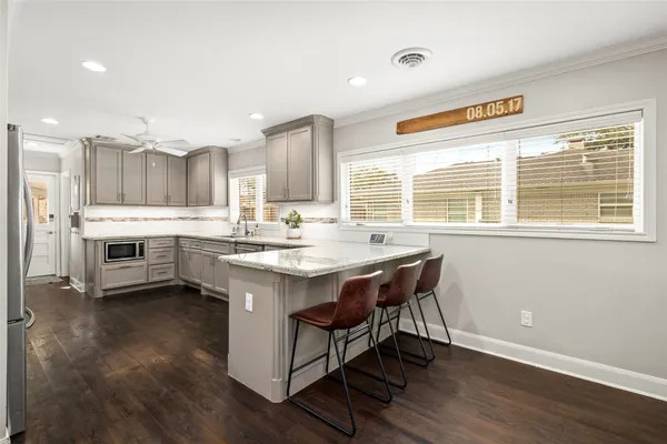 a kitchen with stainless steel appliances granite countertop a stove a sink dishwasher and a refrigerator with wooden floor