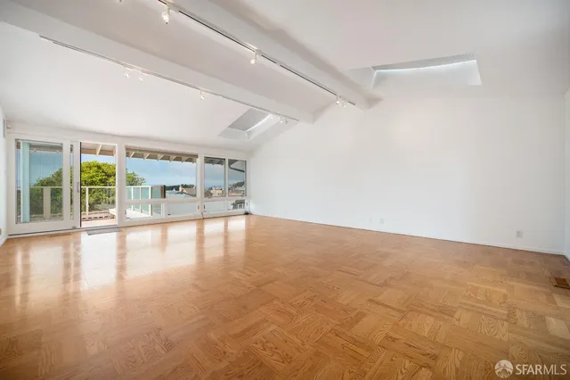 a view of empty room with wooden floor and windows