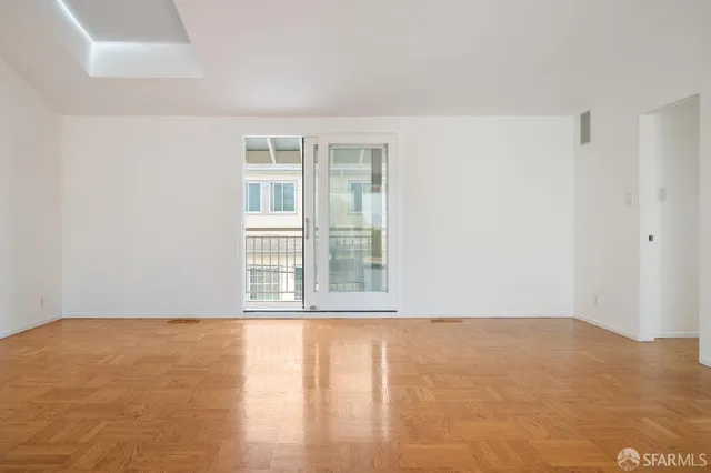 a view of an empty room with window and wooden floor
