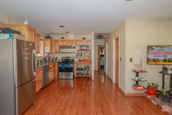 a kitchen with stainless steel appliances wooden floor and a refrigerator