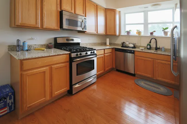 a kitchen with stainless steel appliances granite countertop a sink a stove a microwave cabinets and a window