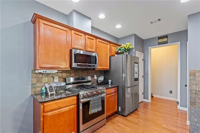 a kitchen with stainless steel appliances granite countertop a stove a refrigerator and a microwave