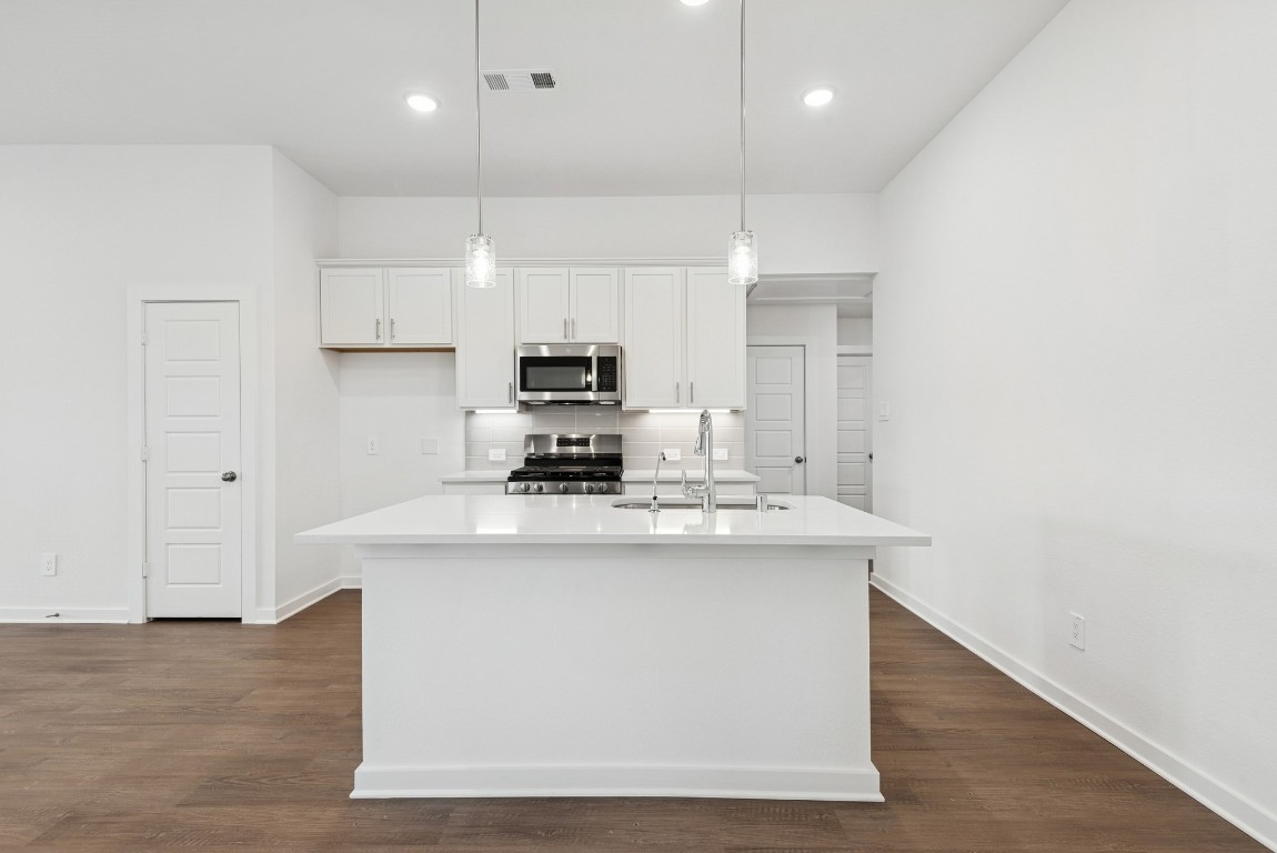 540 Flower Reed Court Magnolia, TX 77354 - Photo 18 of 45 a kitchen with kitchen island a sink a stove a refrigerator and white cabinets