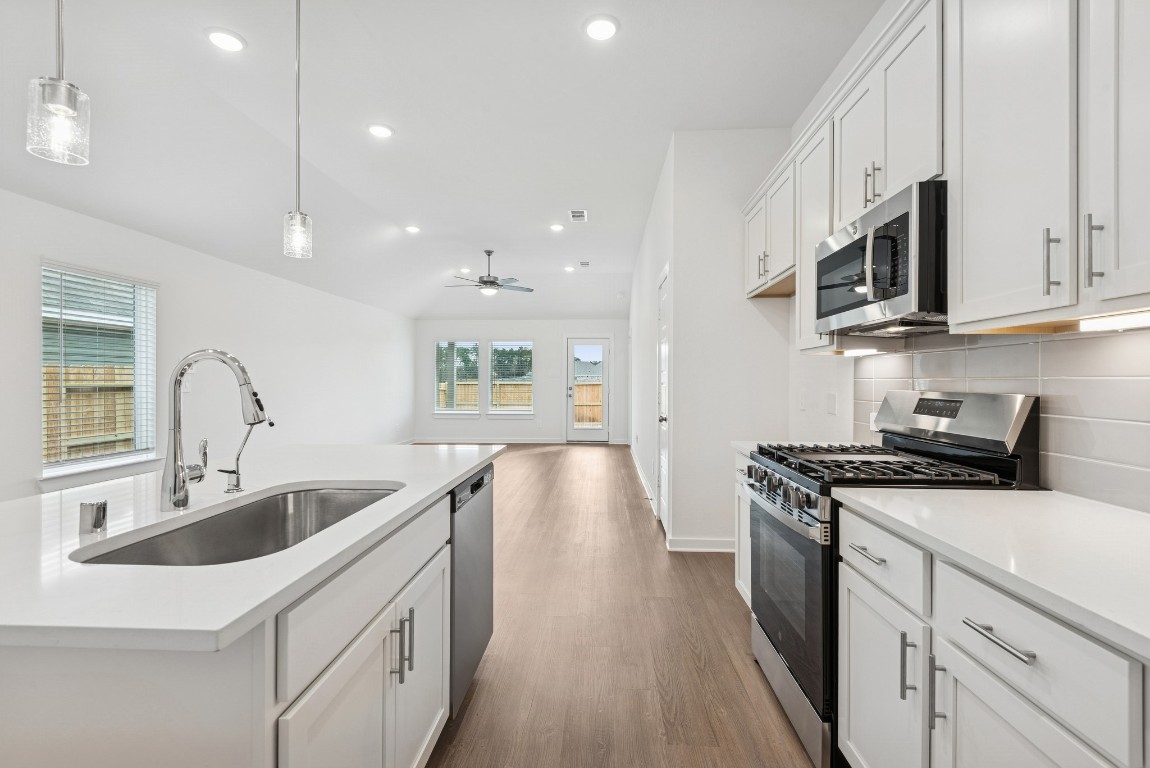 540 Flower Reed Court Magnolia, TX 77354 - Photo 20 of 45 a kitchen with stainless steel appliances granite countertop a sink dishwasher stove and white cabinets with wooden floor
