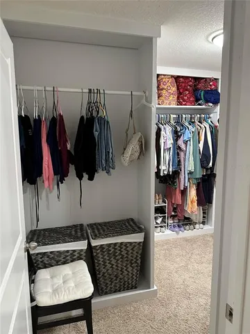 a view of walk in closet with clothes and shoes