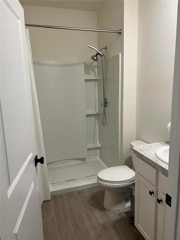 a bathroom with a granite countertop toilet a sink and shower