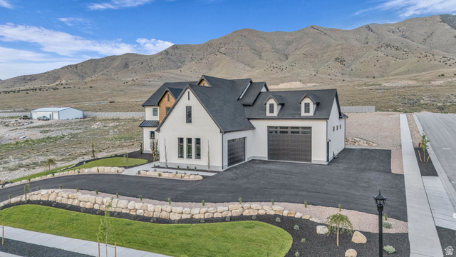 2828 Jojo Road Eagle Mountain, UT 84005 - Photo 56 of 63 Modern farmhouse-style residence featuring a prominent gabled roofline, light-toned siding, and dark-paneled garage doors
