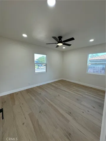 an empty room with wooden floor fan and windows