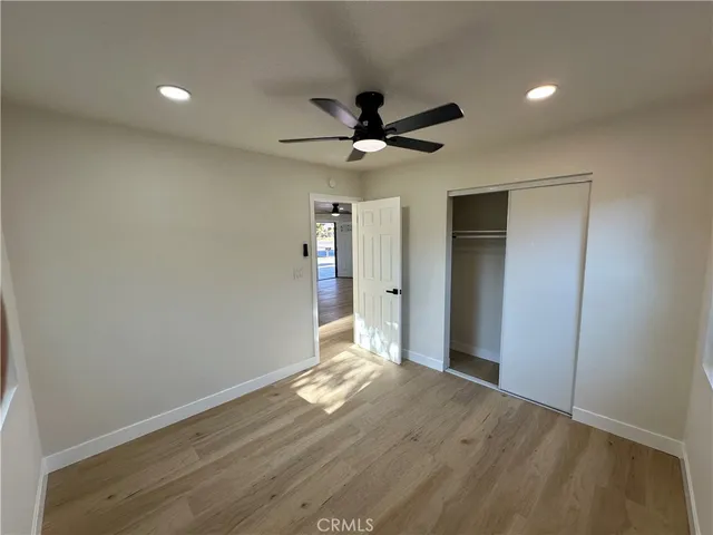 an empty room with wooden floor and a ceiling fan