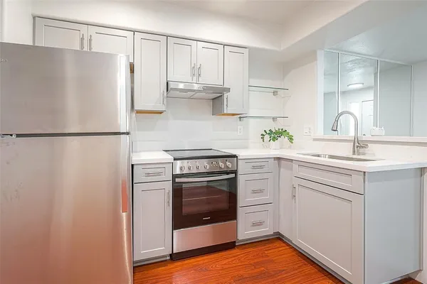 a kitchen that has a sink a refrigerator and a stove top oven