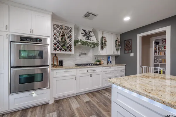a kitchen with stainless steel appliances granite countertop a stove and white cabinets