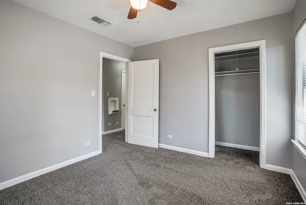 an empty room with closet and a ceiling fan