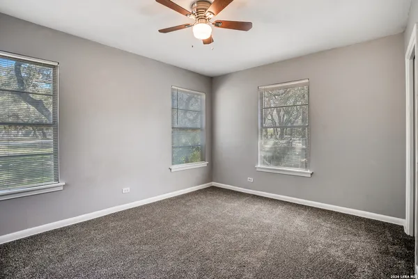 an empty room with windows and fan