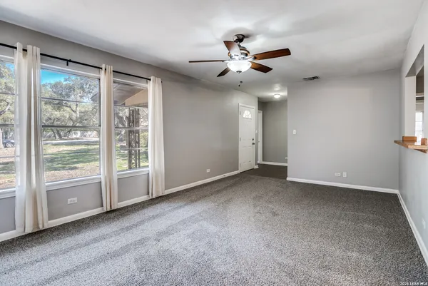 a view of an empty room with chandelier fan and fire place