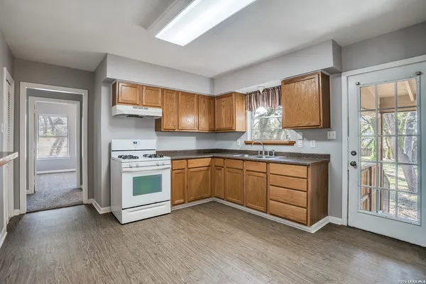 a kitchen with granite countertop a stove a sink and a refrigerator