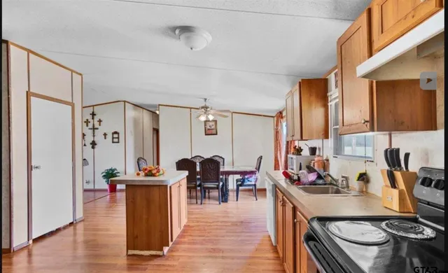 a kitchen with stainless steel appliances granite countertop a stove and a dining table with wooden floor