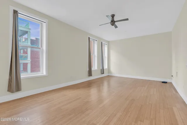 a view of empty room with wooden floor and fan