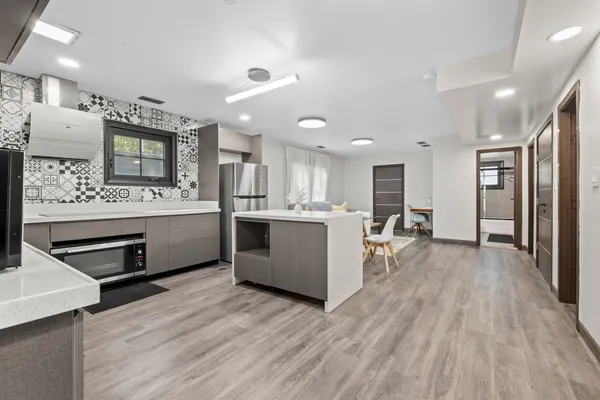 a large white kitchen with a lot of counter space and stainless steel appliances