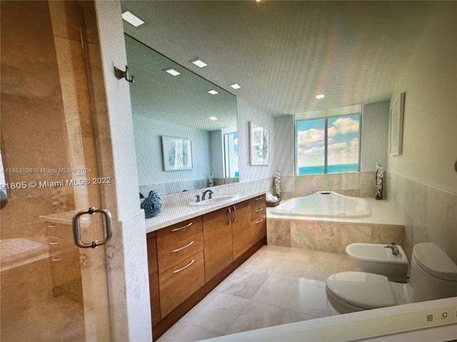 a large bathroom with a granite countertop tub a sink and a large mirror