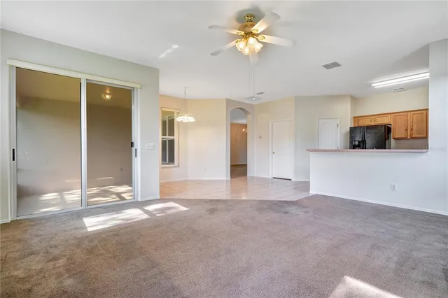 a view of an empty room with window and chandelier fan