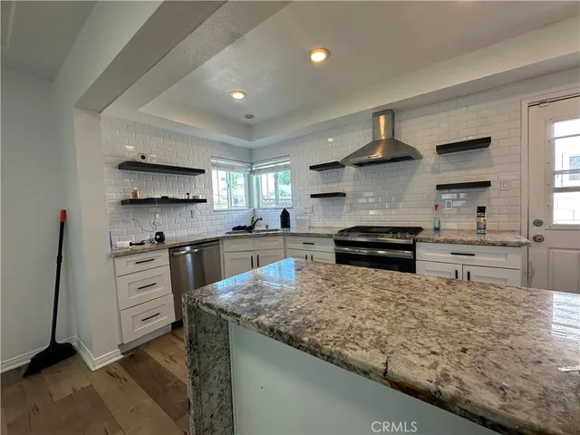 a kitchen with stainless steel appliances granite countertop a stove top oven a sink a counter space and cabinets