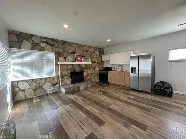an empty room with wooden floor fireplace and windows