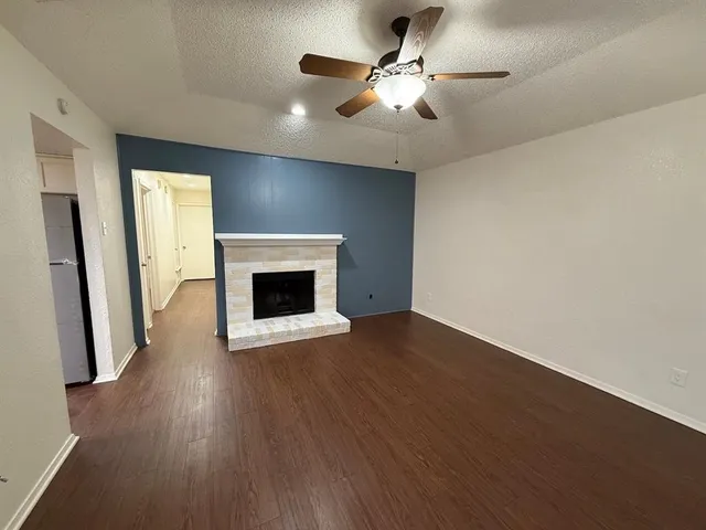 a view of an empty room with wooden floor and a fireplace