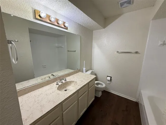 a bathroom with a granite countertop sink a toilet and a mirror