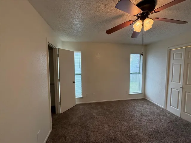 a view of an empty room and chandelier fan