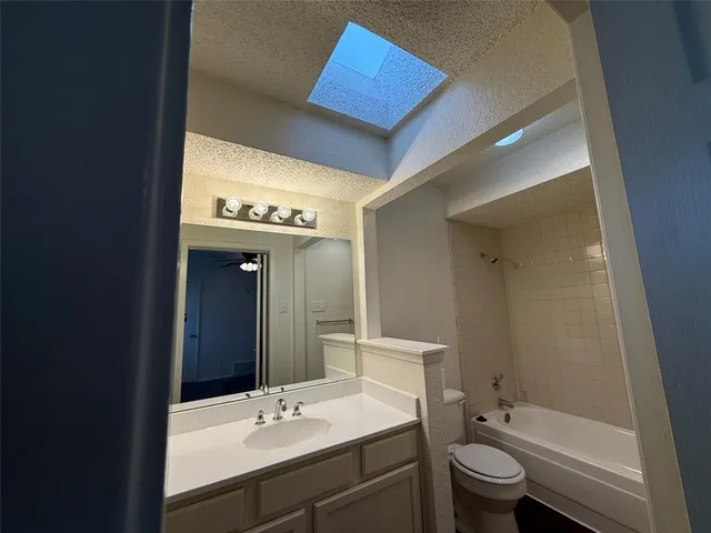 a bathroom with a bathtub shower sink mirror vanity and toilet