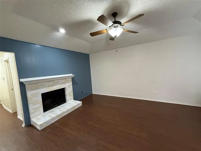 a view of an empty room with wooden floor and a fireplace