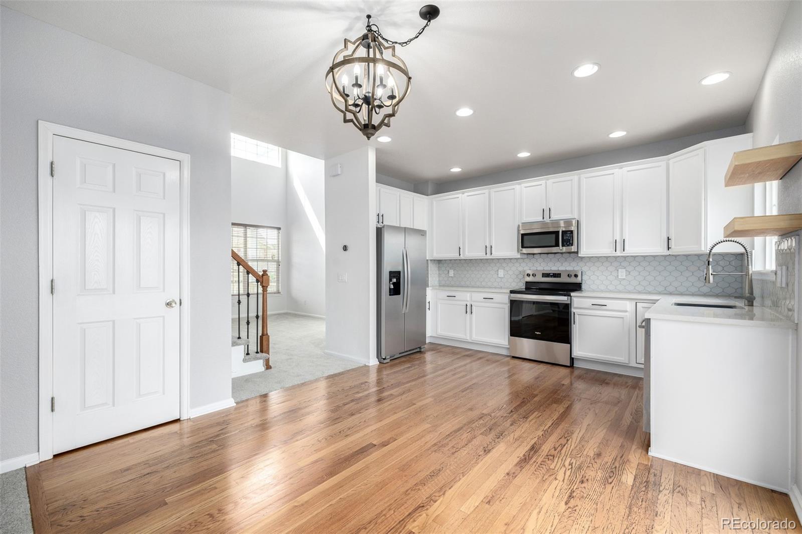 1041 Riddlewood Road Highlands Ranch, CO 80129 - Photo 17 of 50 a kitchen with stainless steel appliances granite countertop a refrigerator a stove oven a sink dishwasher and white cabinets with wooden floor