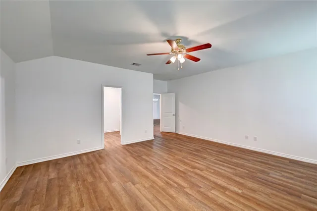 an empty room with wooden floor and fan