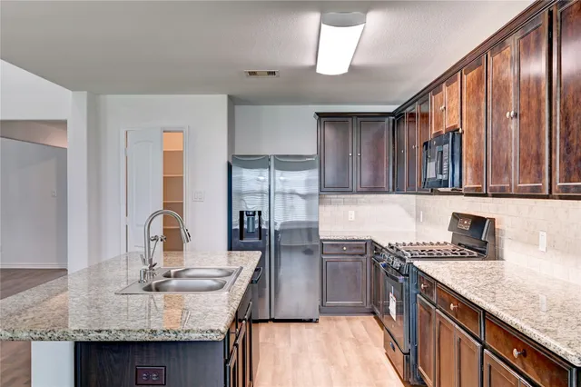 a kitchen with stainless steel appliances granite countertop a sink stove and cabinets