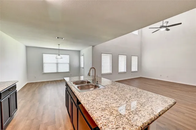 a room with kitchen island granite countertop wooden floor and a sink