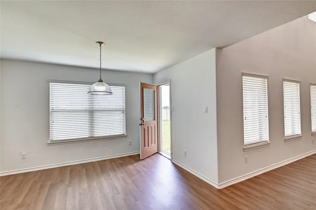 a view of an empty room with a window and wooden floor