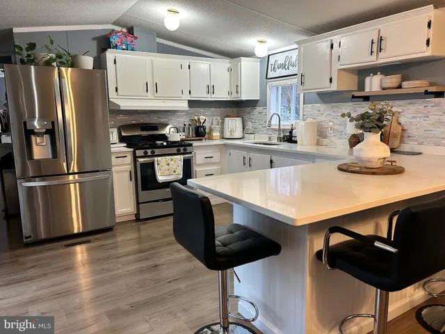 a kitchen with stainless steel appliances a stove a sink a refrigerator and cabinets