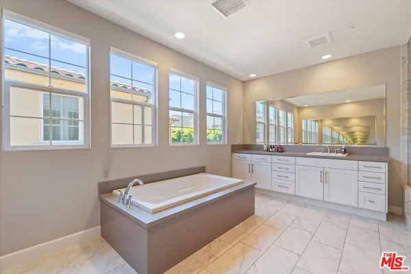 a spacious bathroom with a tub sink and mirror