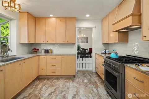 a kitchen with granite countertop a stove top oven sink and cabinets