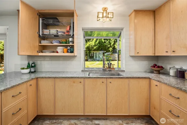 a kitchen with granite countertop white cabinets and window