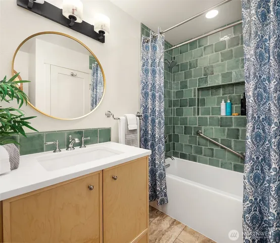 a bathroom with a granite countertop sink a mirror a bathtub and shower